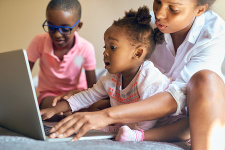I can do it on my own, mommy. an affectionate young family using a laptop together at home.
