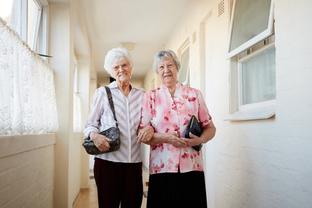Life is better with a friend by your side. Portrait of two happy elderly women carrying their bags and getting ready to go out.の写真素材