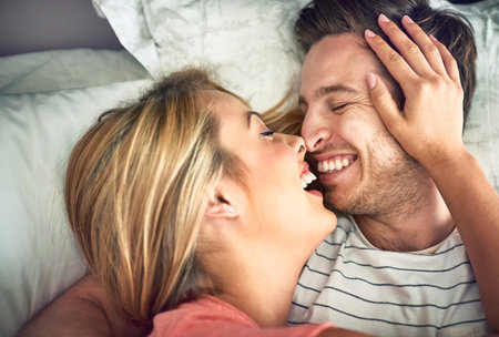 Live, love, laugh. a happy young couple sharing an affectionate moment in bed.の写真素材
