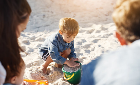 Hes a master at building sandcastles. an adorable little boy building sandcastles with his family at the beach.の写真素材
