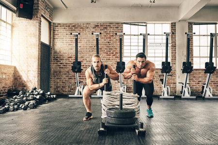This is second nature to us. two fit and determined young men making use of weights to workout in a...