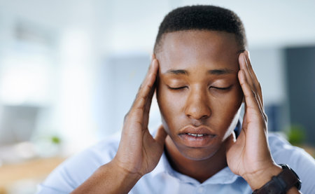 Keeping a clear mind always works. a young and stressed businessman suffering from a headache while...