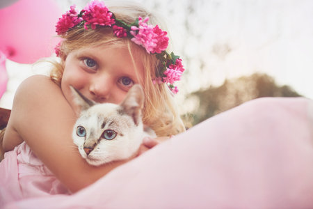 Childhood bliss. a happy little girl holding a kitten and looking at the camera outside in the nature.の写真素材