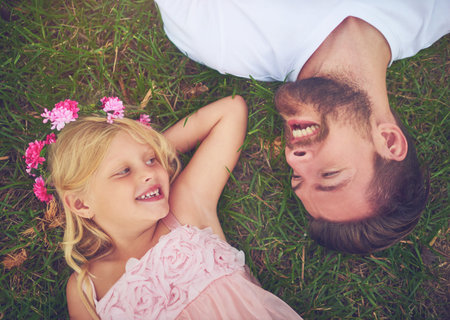 Her dad is her best friend. a happy daughter and father lying on the ground looking at one another outside in nature.の写真素材