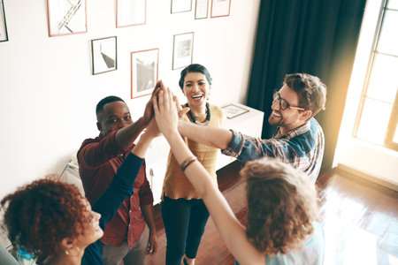 Were going to keep on winning. a group of designers high fiving together in an office.