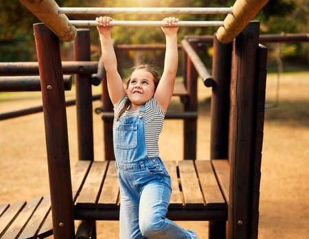 Playing is a childs favourite way of learning. a little girl playing on the jungle gym at the park.の写真素材