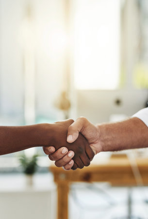 Shifting business to the fore through a new merger. Closeup shot of two unrecognizable businessmen shaking hands in an office.の写真素材