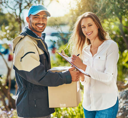 Looks like Ive found the best delivery service around. Portrait of a courier making a delivery to a young woman.の写真素材