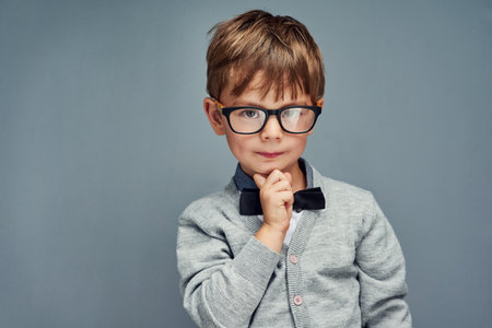 Nerd is the new cool. Studio portrait of a smartly dressed little boy posing confidently against a gray background.の写真素材