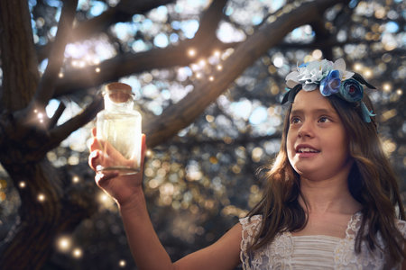 Theyre glowing just like fairies. a little girl catching fireflies in a jar outside.の写真素材
