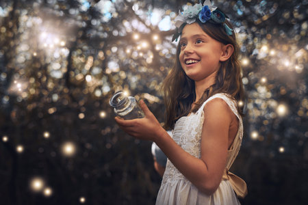 Fun with fireflies. a little girl catching fireflies in a jar outside.の写真素材