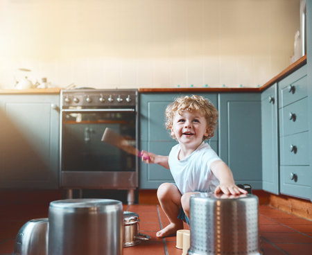 Let them be young and noisy. Portrait of an adorable little boy playing with pots in the kitchen.の写真素材