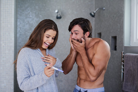 Its a miracle. a joyful young couple looking surprised after taking a pregnancy test at home.