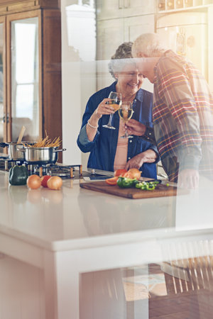 Many meals and memories have been shared between them. a smiling senior couple cooking together in their kitchen at home.の写真素材
