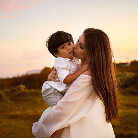 Mother and son, a bond that can never be broken. a young mother kissing her son on the cheek outdoors.の写真素材