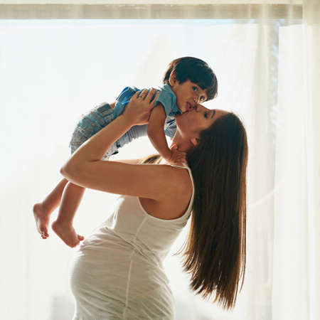 Mommy loves you to the moon and back. a pregnant woman playing with her little boy in her bedroom at home.の写真素材