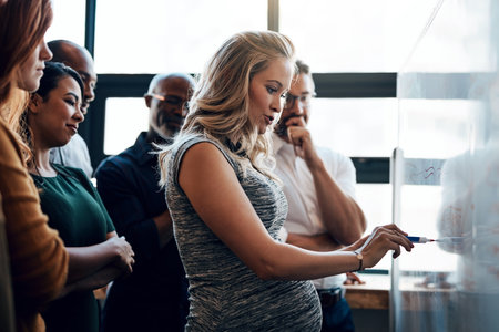 Keeping them updated with any new developments before she leaves. a pregnant businesswoman giving a presentation in the boardroom.の写真素材