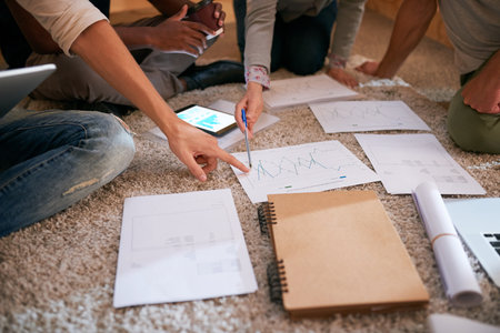 Planning their success for the long-term. Closeup shot of a group of unrecognisable businesspeople brainstorming on the floor in an office.の写真素材