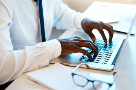 His typing game is on. Closeup of an unrecognizable man working and typing on his laptop at his desk...