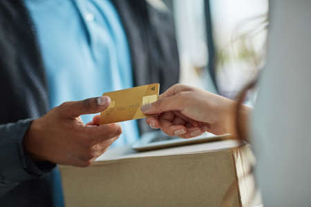 Operating with a cash-on-delivery service. a customer using a credit card to pay for a delivery made by a courier.の写真素材