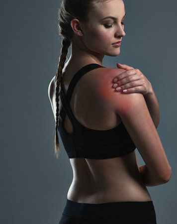 Workout injuries can happen to anyone. a sporty young woman suffering from a shoulder injury.の写真素材