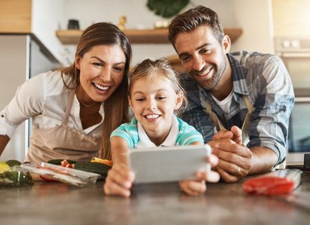 Everybody say cheese. a happy young family posing for a selfie while cooking together in their kitchen.の写真素材