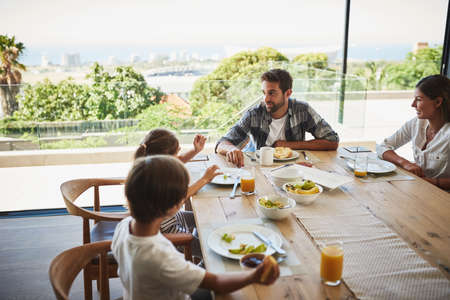 Starting the day together. a family having breakfast together at home.の写真素材
