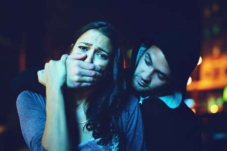 Now she truly knows crime. Portrait of a frightened young woman with her assailants hand over her...