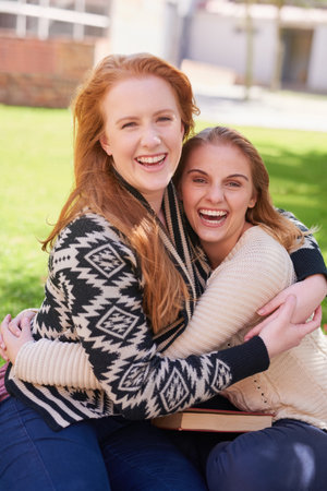 Forging life long friendships at college. two happy friends hugging outdoors.の写真素材