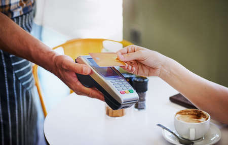 Paying is as simple as a tap. an unidentifiable young woman using her credit card to pay for coffee...