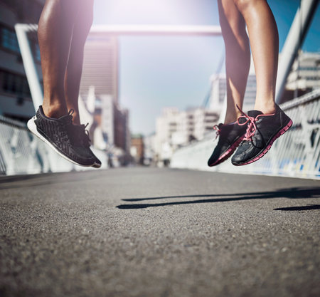 Raise your game. Legs-only shot of two sporty people jumping on a bridge.の写真素材