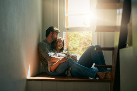 I cherish every moment with you. an affectionate young couple holding each other at home in the sunlight.の写真素材
