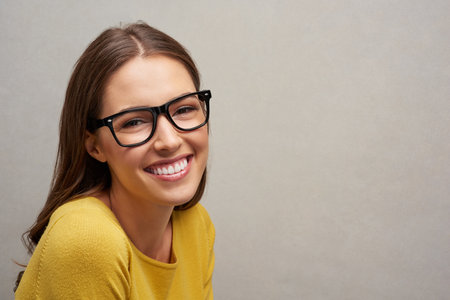 Looking great against grey. Studio portrait of an attractive young woman posing against a grey background.の写真素材