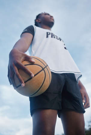 Basketball athlete ready for training, game and competition on sports court from below outdoor. Thinking, focus and fitness young black man with motivation, mindset and goal to play, win and have funの写真素材