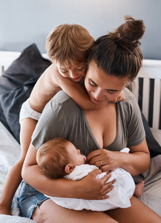 Pure, unfiltered love. a young woman bonding with her two sons at home.の写真素材