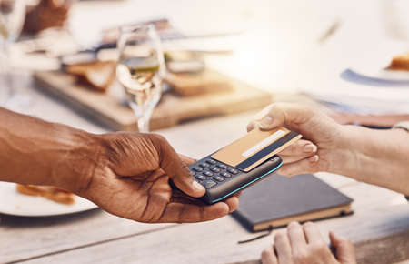 Restaurant customer payment with credit card on machine or digital tech for contactless and secure payment while fine dining. Food business manager or waiter hands using 5g to tap or scan a bank cardの写真素材