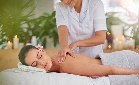 Unwind and enjoy the tranquil times. an attractive young woman enjoying a back massage at a spa.の写真素材