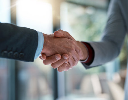 Merging for success. two unrecognizable businessmen shaking hands after making a deal in the office.の写真素材