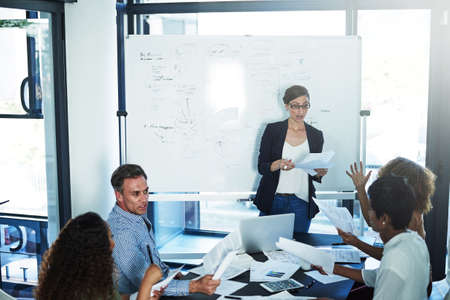 Caught up in the paperwork. a group of focussed businesspeople attending a colleagues presentation...