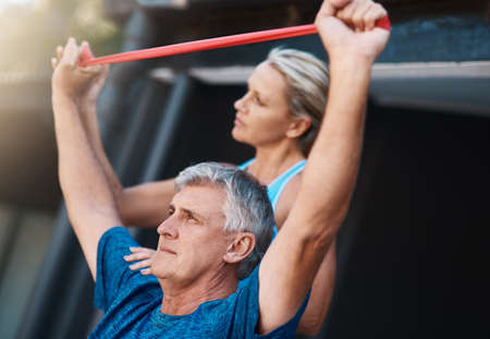 Were always stronger when we work together. a mature man stretching his arm muscles with an elastic...