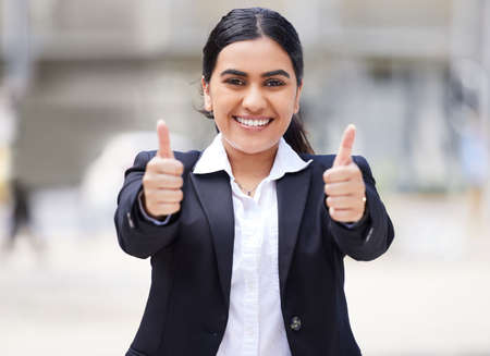 Thumbs up emoji for motivation, success and thank you for support in urban city. Portrait of a happy, smile and excited business woman, winner and worker with goal, yes vote and trust for good newsの写真素材