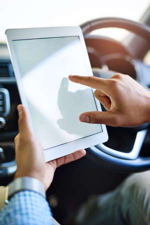 Getting work done even when away from his desk. an unidentifiable man using a digital tablet while...