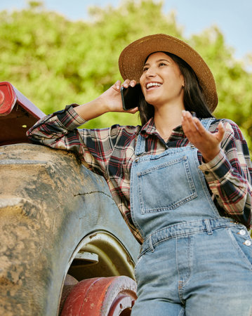Agriculture, sustainability and farmer talking on phone while working on a farm with a tractor. Wellness, health and agro woman networking with a mobile while standing on a field in the countryside.の写真素材