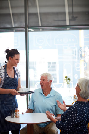 The service is speedy and friendly. a senior couple being served by a waitress.の写真素材