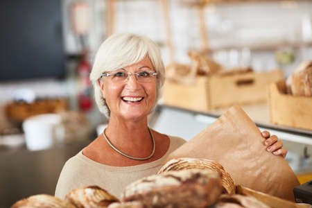 We only serve it fresh. Portrait of a happy senior woman working in a bakery.の写真素材