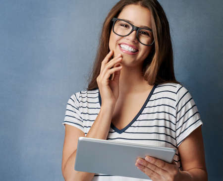 Can I imagine life without it Nah. Studio shot of a young woman using her digital tablet against a...