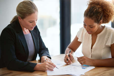 Making deals happen. two businesswoman sitting in an office discussing paperwork.