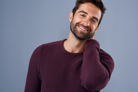Happy and handsome. Whats not to love. Studio shot of a handsome and happy young man posing against a gray background.の写真素材