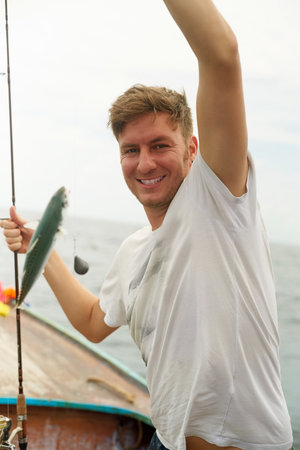 Every catch counts. Cropped portrait of a handsome young man fishing while out at sea on his boat.
