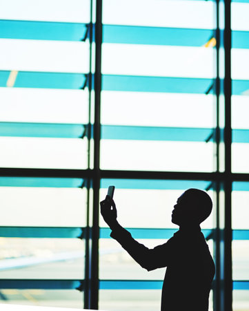 Making connections at the airport. an unidentifiable traveler using his smartphone in an empty airport lounge.の写真素材